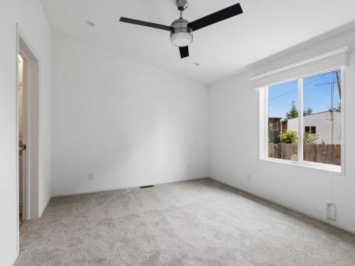An empty room with white walls and a ceiling fan.