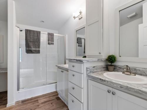 A bathroom with white cabinets and hardwood floors.