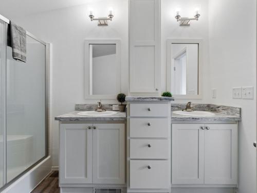 A white bathroom with two sinks and a walk in shower.