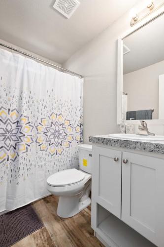 A bathroom with a yellow and white shower curtain.