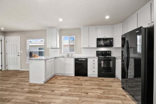 A white kitchen with black appliances and hardwood floors.